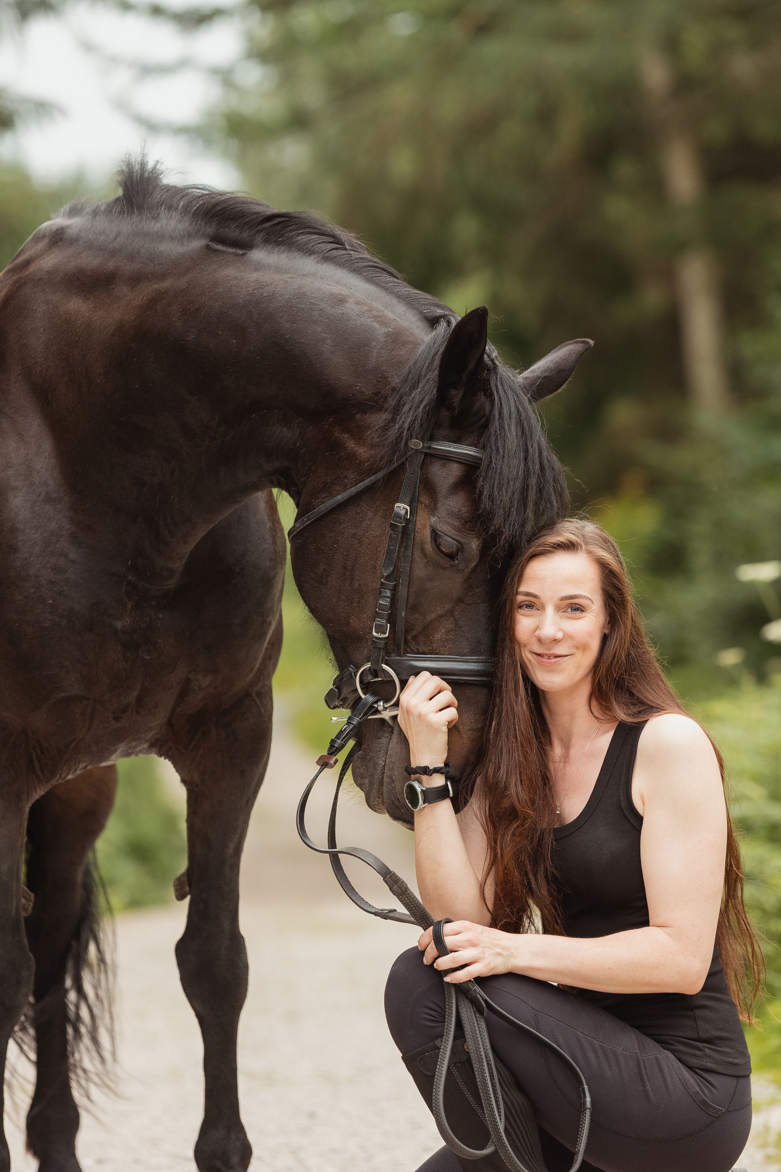A beautiful moment captured between a dark horse and rider on a wooded trail.