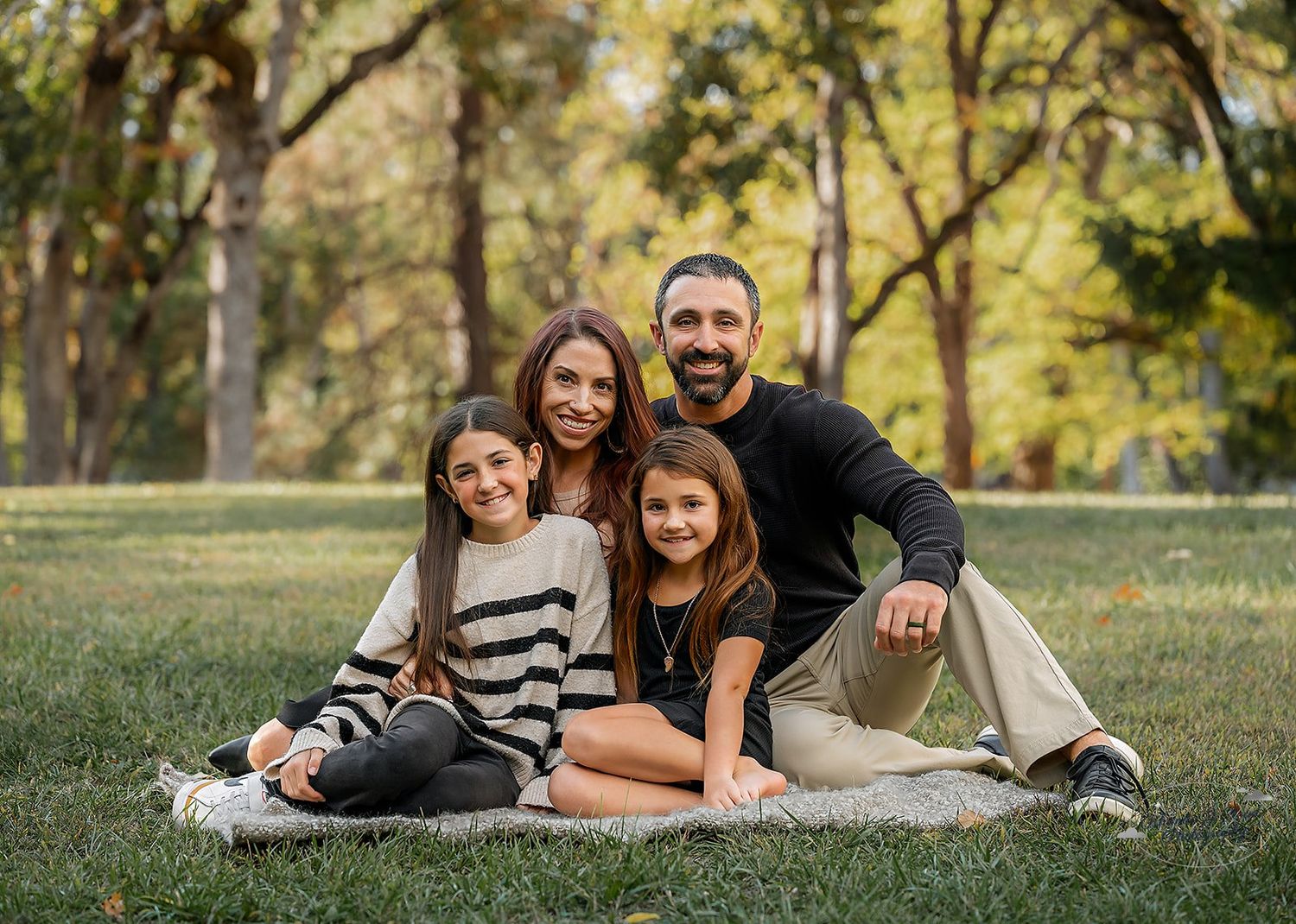 family of four posing for family portrait in front of Oak Trees