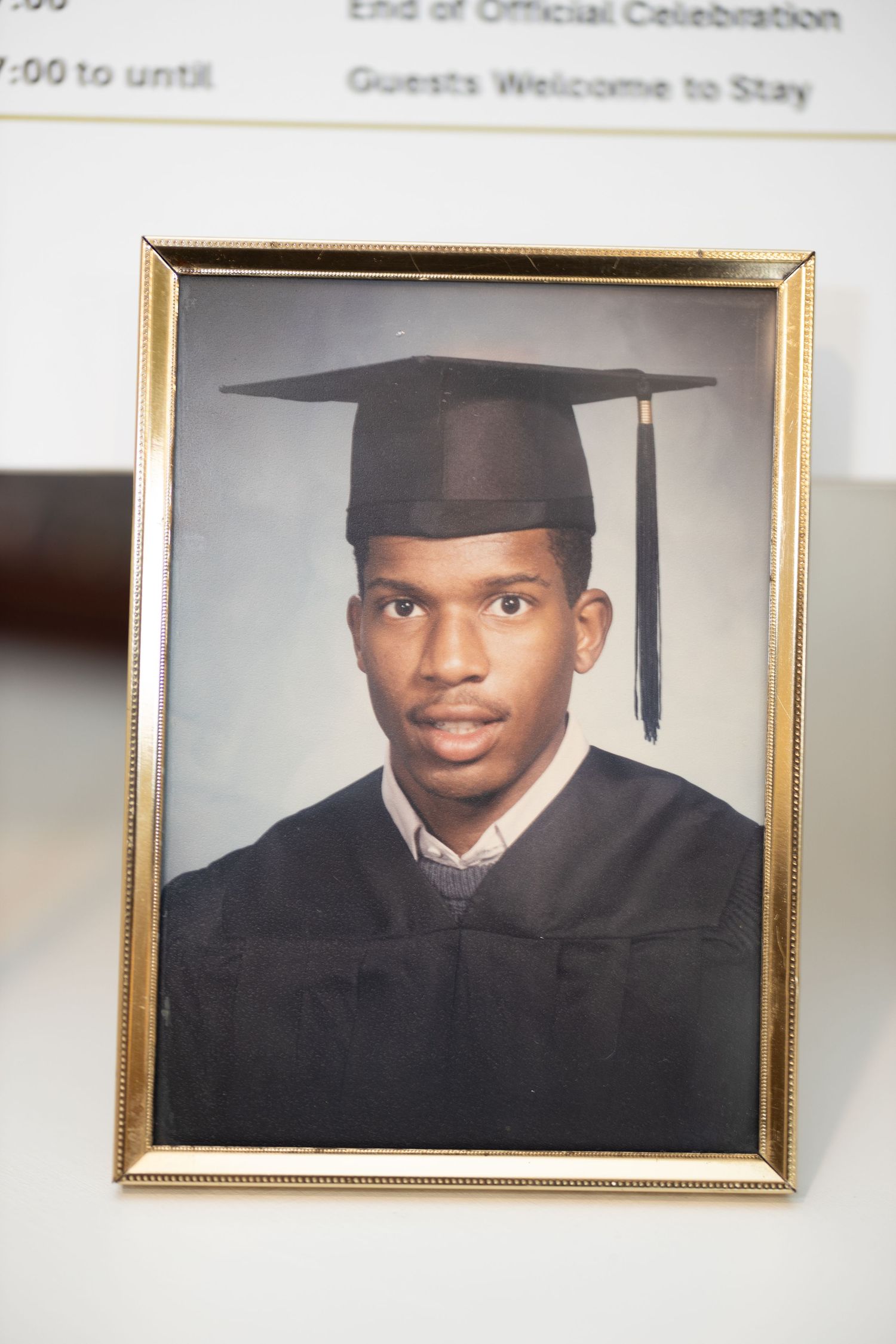 Framed graduation portrait in academic cap and gown displayed on table.