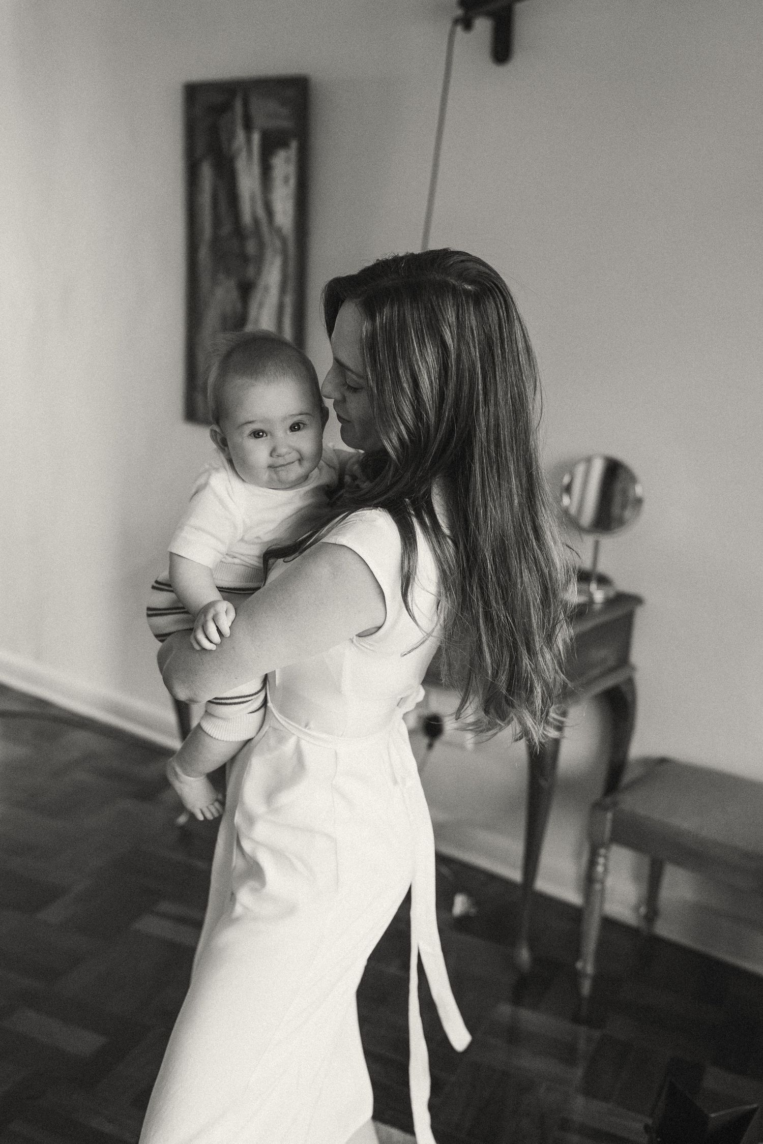 Black and white family portrait showing playful interaction in minimalist indoor setting.