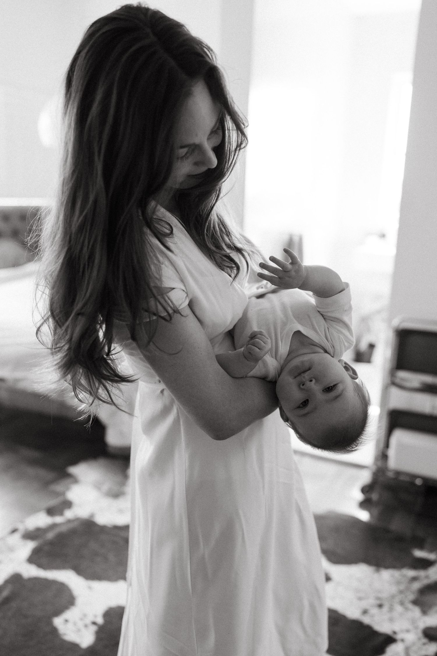 Intimate family portrait in white dress against bright window light.