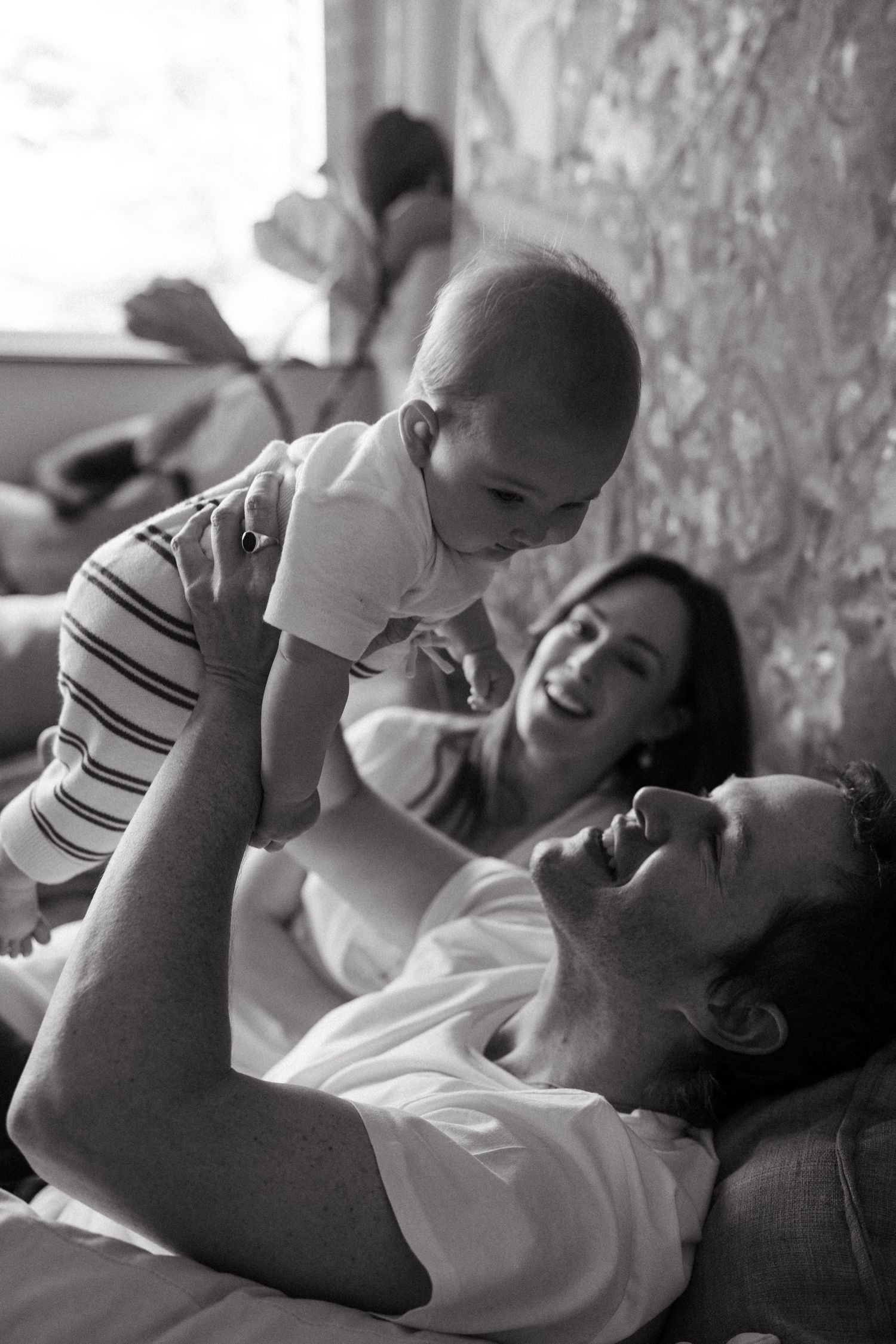 Black and white sequence of tender parent-child playtime moments on a couch.