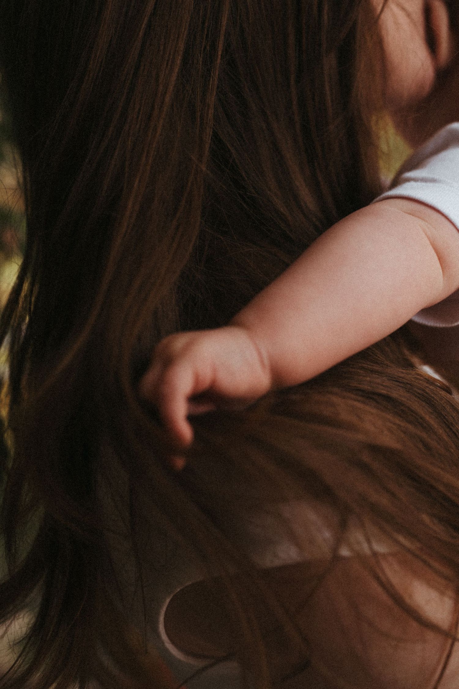 Artistic close-up of small hands touching long dark hair.