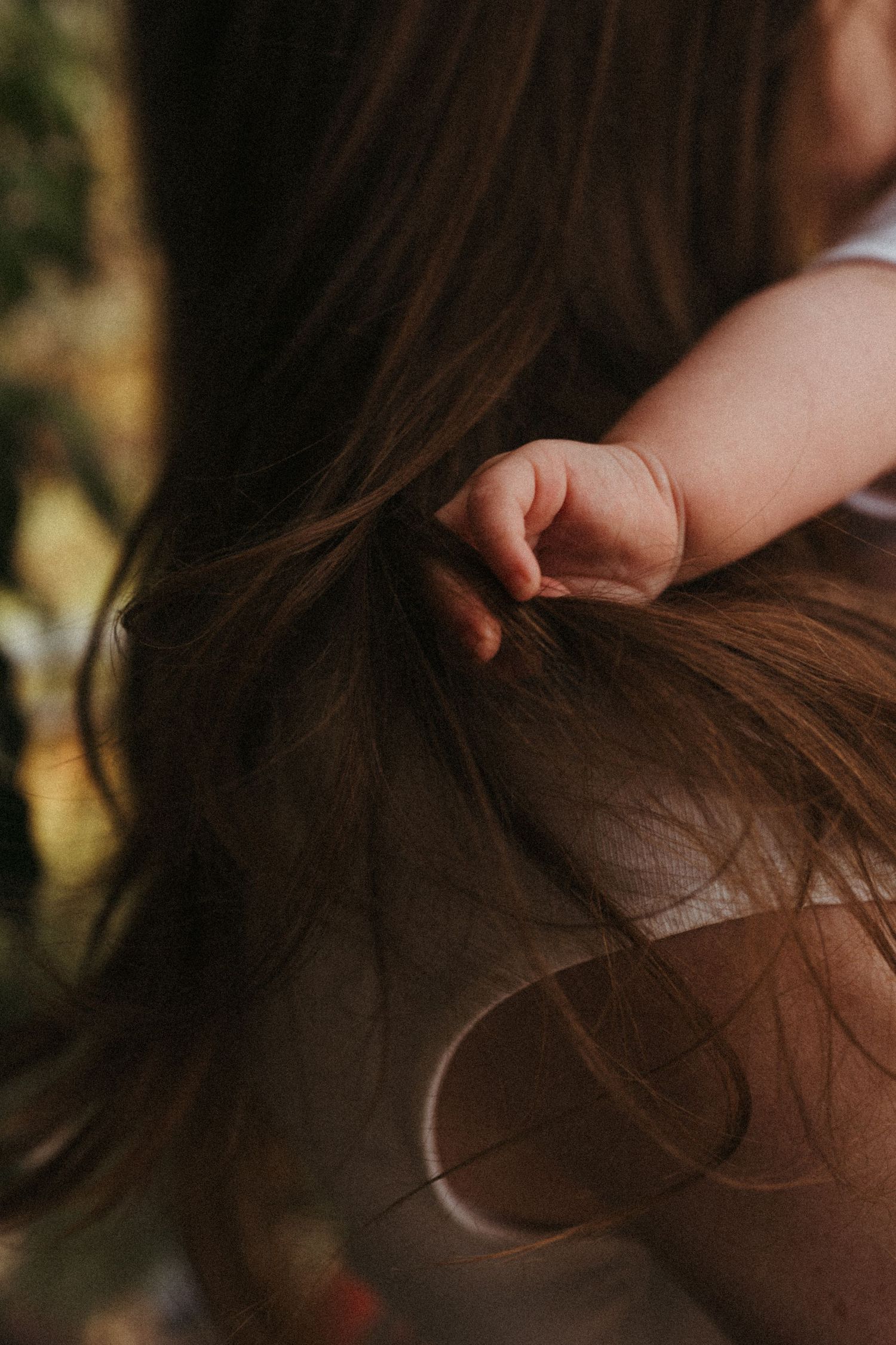 Detailed shots focusing on tiny fingers playing with dark brown hair.