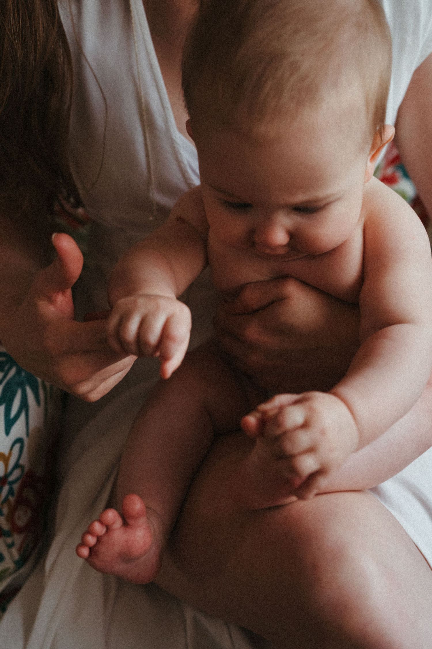 Close-up artistic black and white photo showing tender details of a baby's tiny hands and feet.