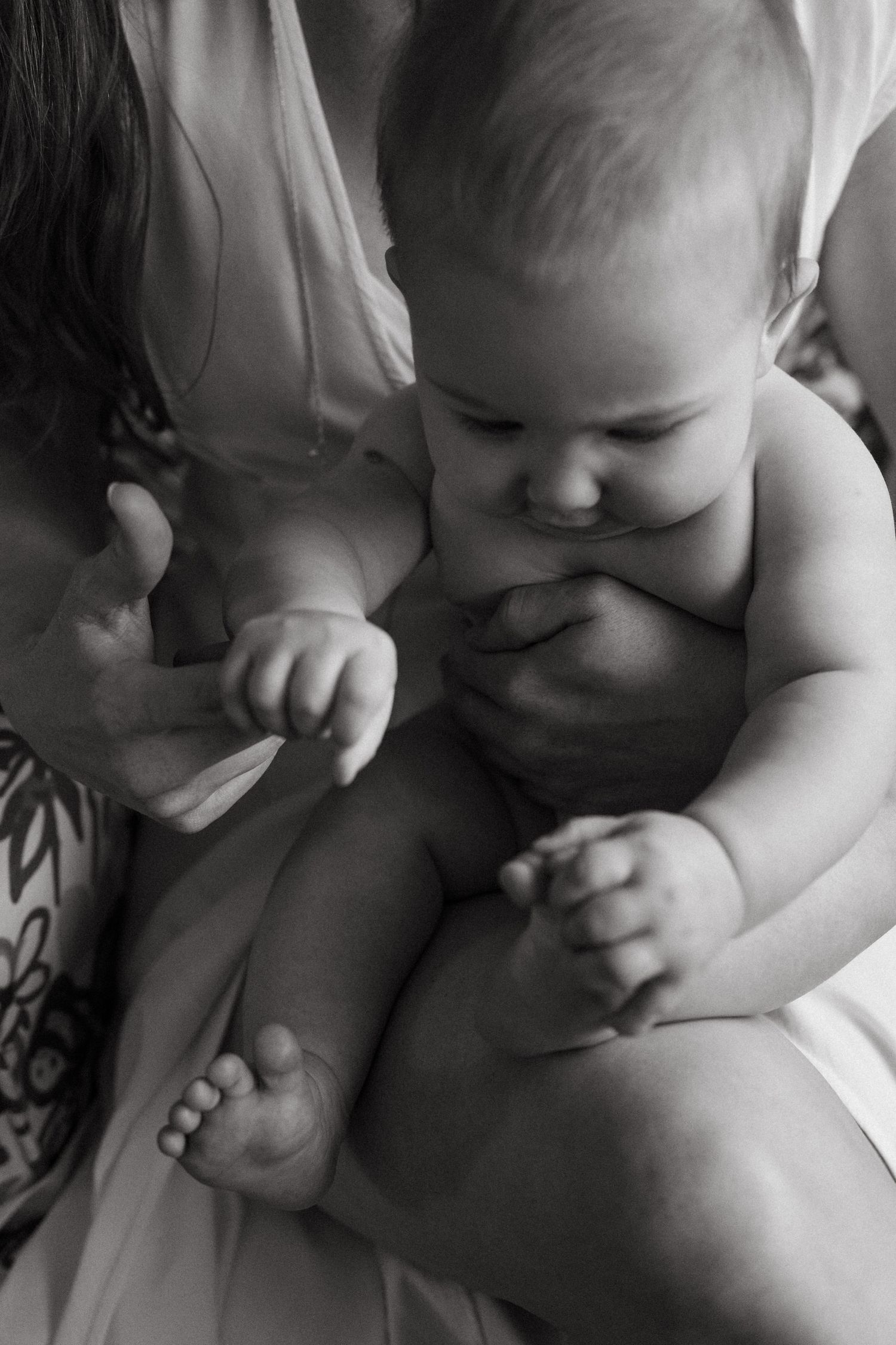 Close-up artistic black and white photo showing tender details of a baby's tiny hands and feet.