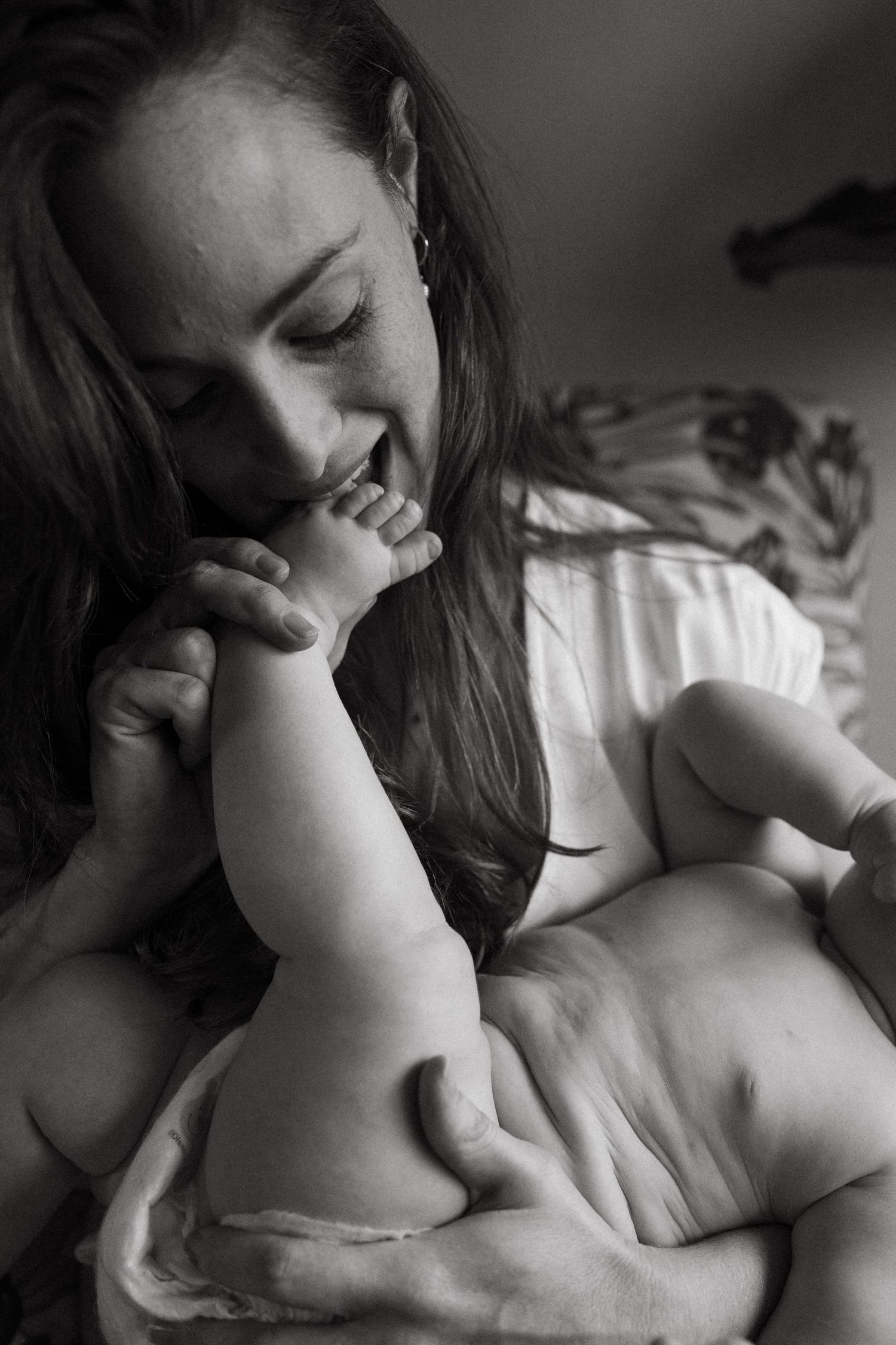 Loving moment between parent and baby captured in black and white as tiny feet are kissed.