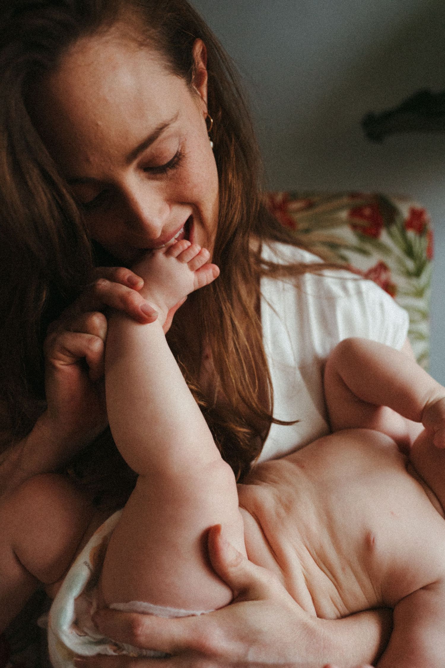 Intimate portrait of parent snuggling and kissing baby's feet in warm natural light.