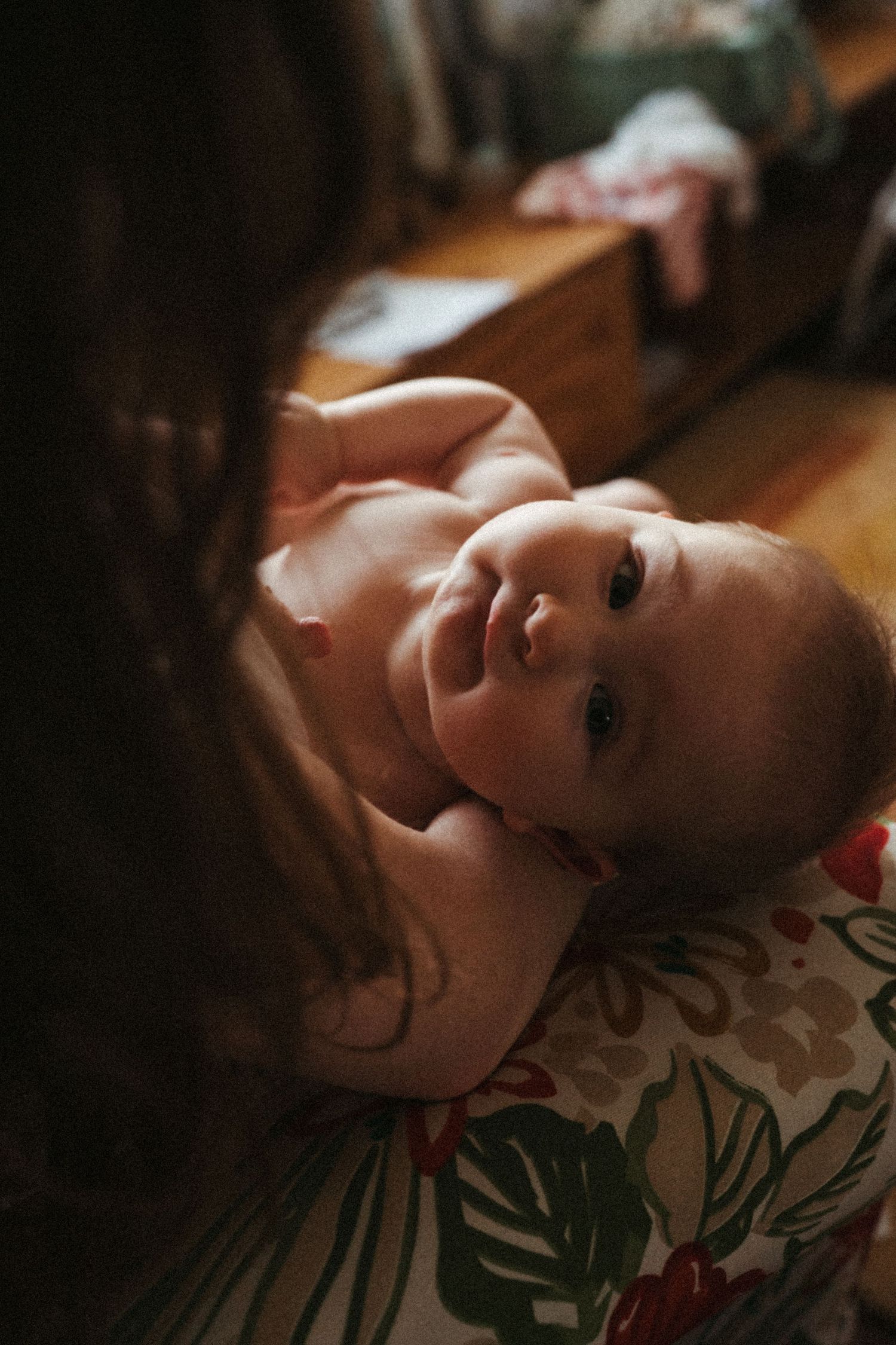 Baby resting on floral patterned fabric in moody lighting.