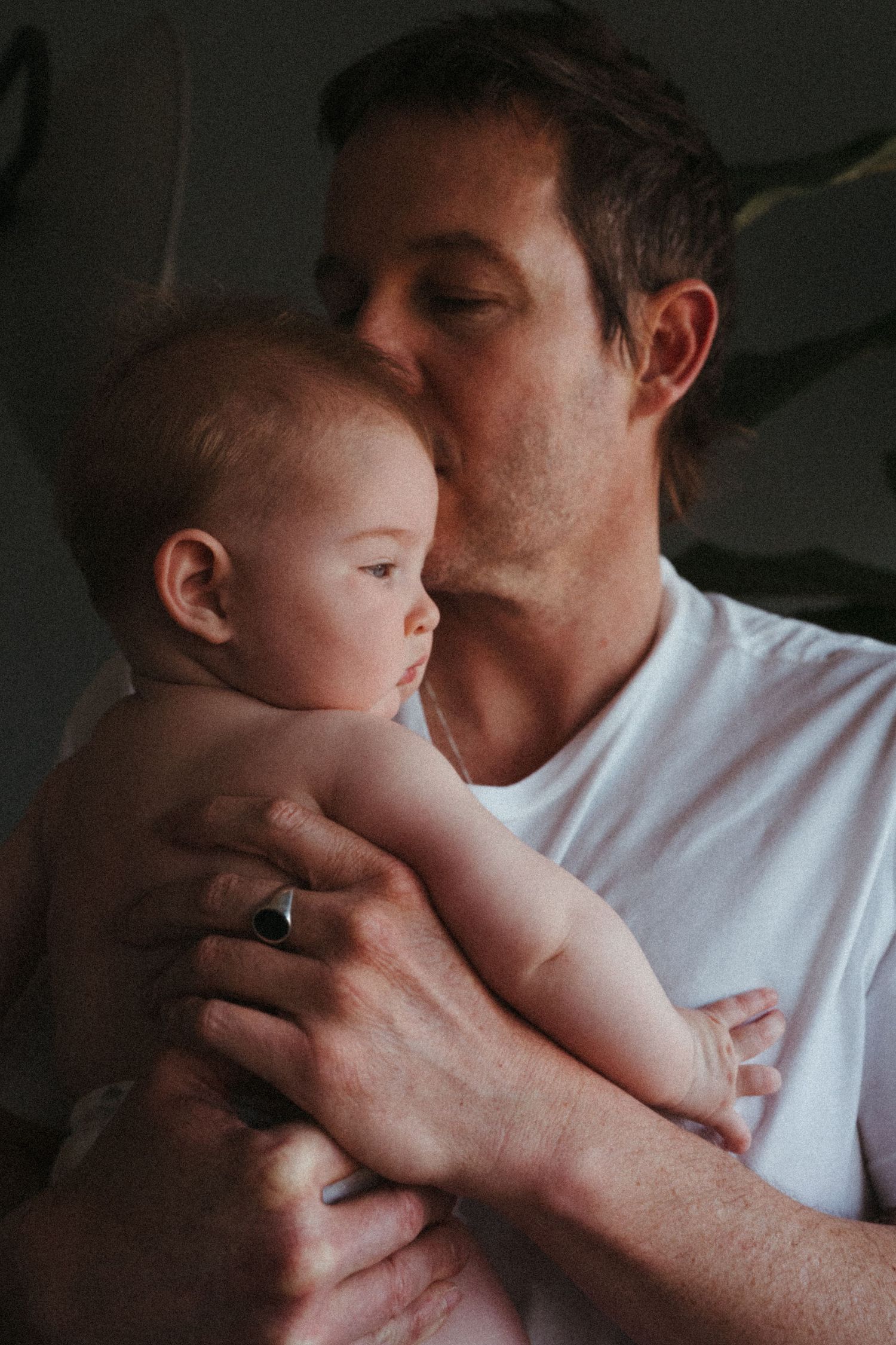 An intimate portrait of a parent giving their baby a gentle kiss on the head.