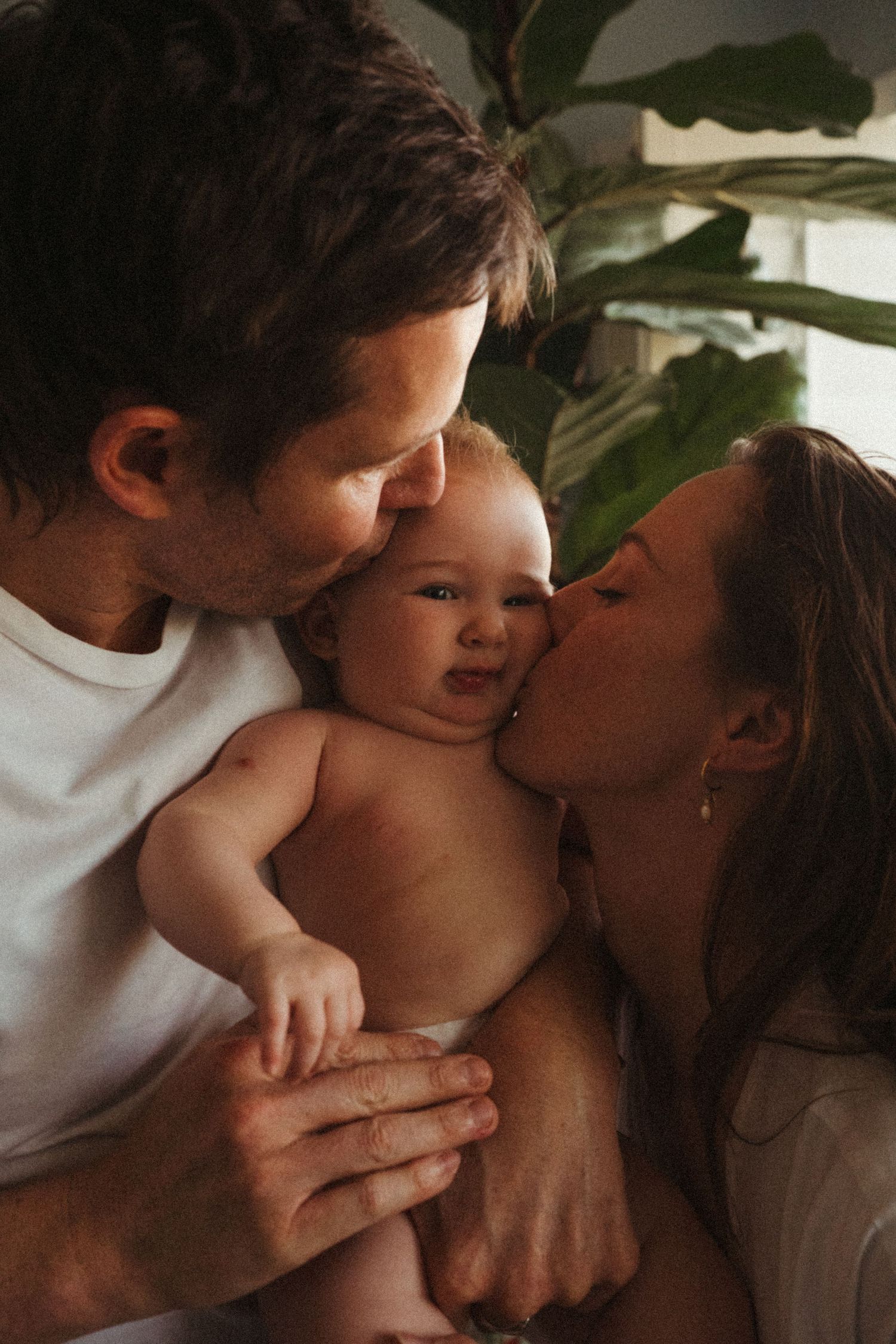 An intimate family portrait showing parents sharing a loving moment with their baby.