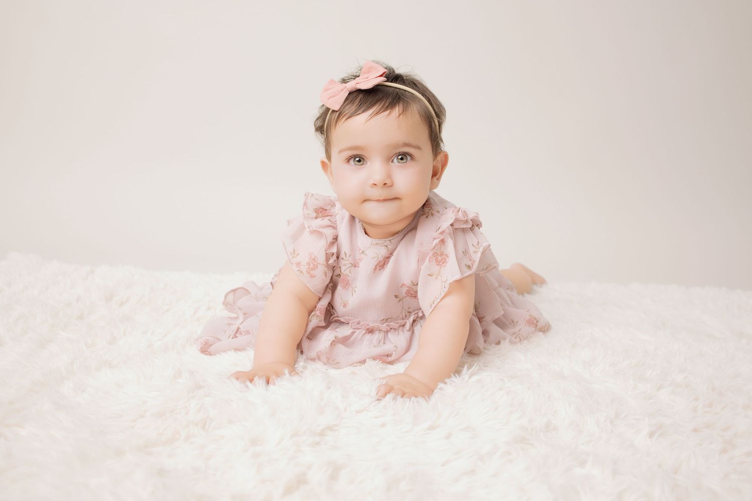 Newborn wrapped in red knit blanket sleeping peacefully on fluffy brown textured backdrop.