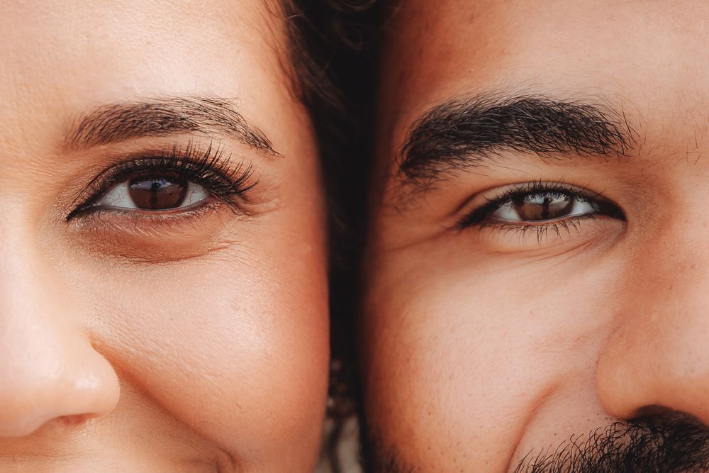 Close-up portrait of a man and woman side by side, showcasing their brown eyes and defined eyebrows.