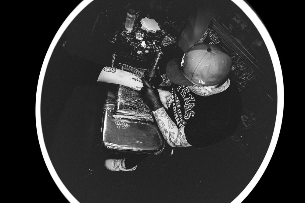 Overhead black and white photograph showing opened books, papers, and a pumpkin arranged on a dark surface.