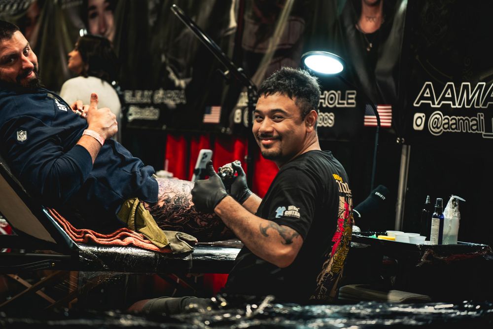 MMA competitor in black t-shirt smiles while preparing for competition backstage at event.