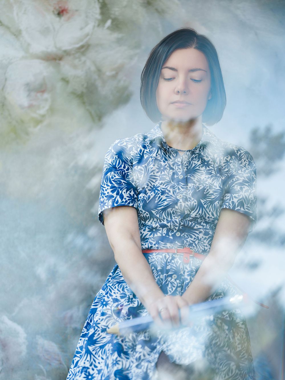 Dreamy portrait in blue and white floral dress with soft focus and ethereal smoke effects creating mystical atmosphere.