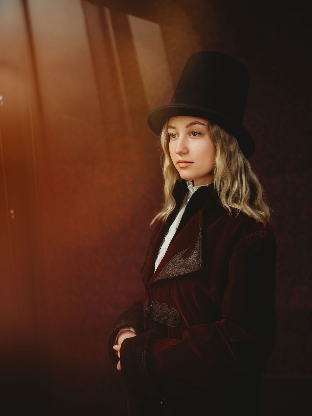Artistic portrait series in dark moody lighting featuring a person wearing a black hat against a warm brown background.