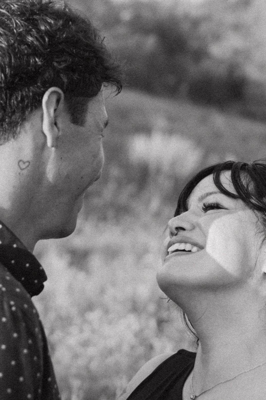 Black and white candid moment captured between couple sharing a joyful outdoor interaction.