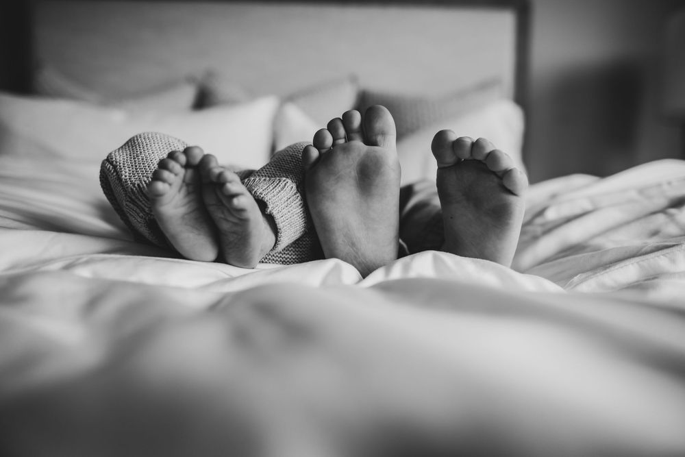 Black and white photo of someone sleeping peacefully in white bedding with soft natural lighting.