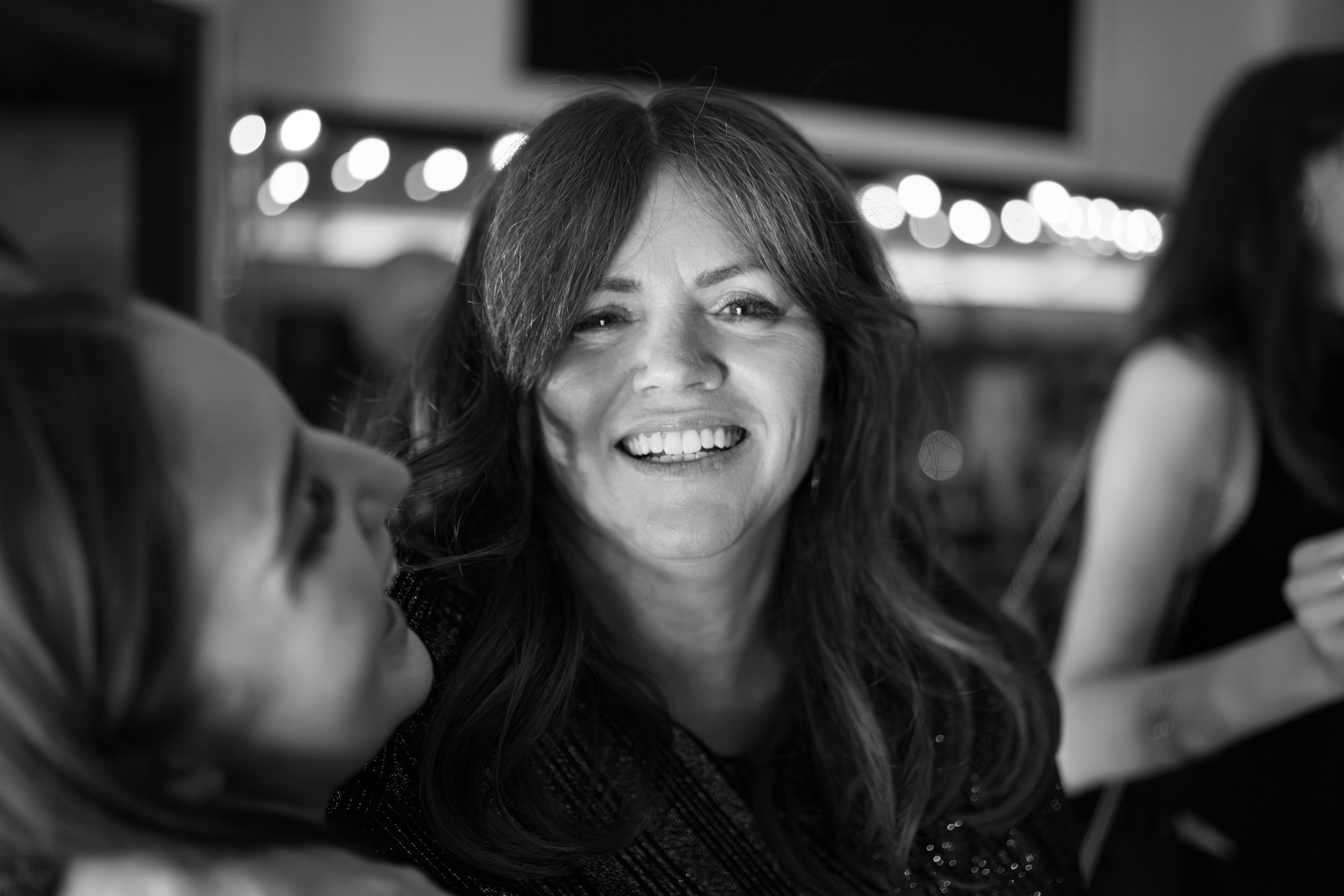 A candid black and white portrait of joy and laughter at an evening gathering.