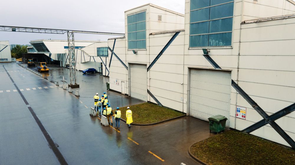 Industrial buildings with yellow barriers and safety equipment on a rainy day.