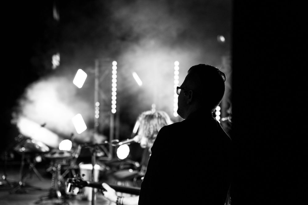 Silhouette of a person watching a concert with bright stage lights in the background.