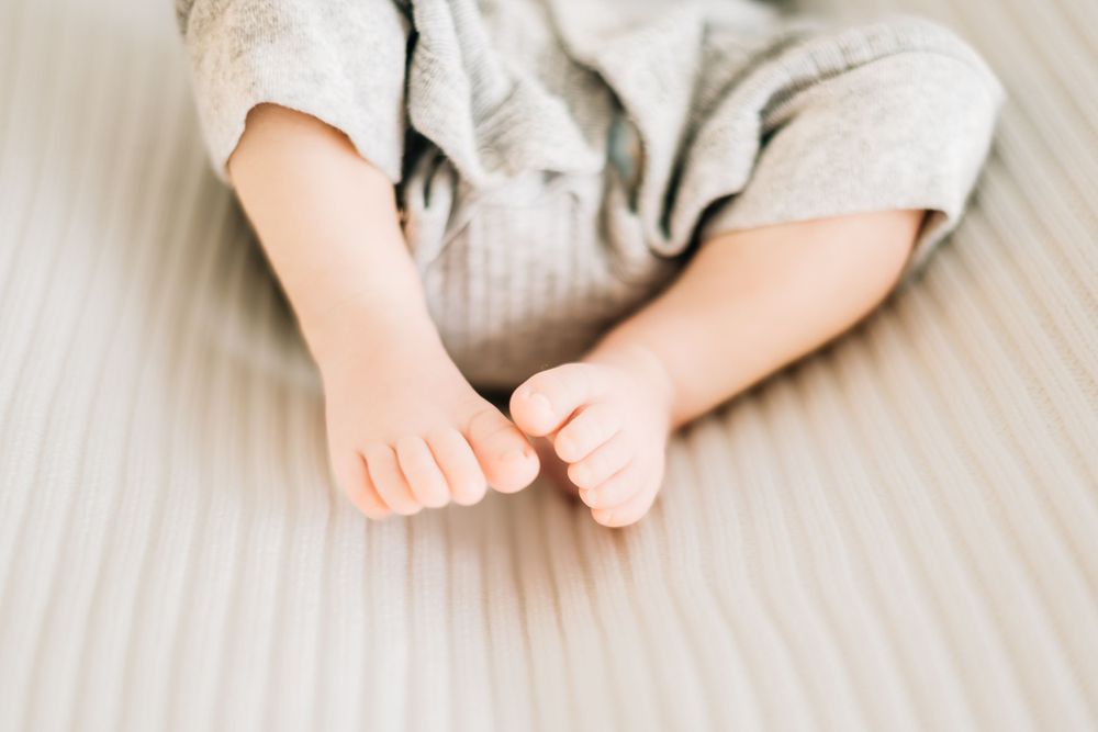 Close-up of tiny baby feet and toes against white ribbed fabric background.