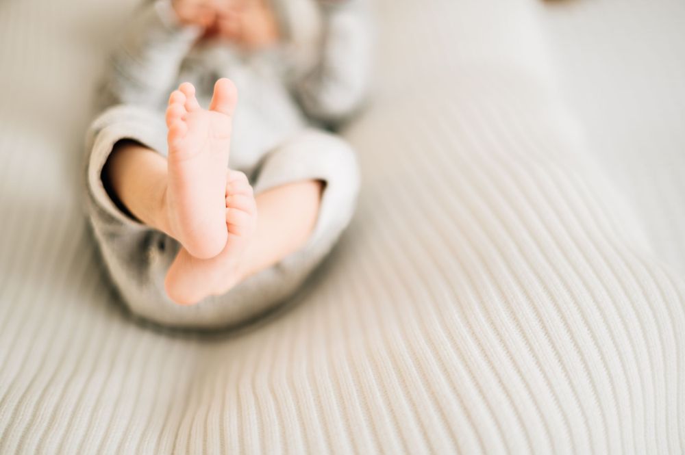 Detail shot of infant's bare feet against soft textured surface.