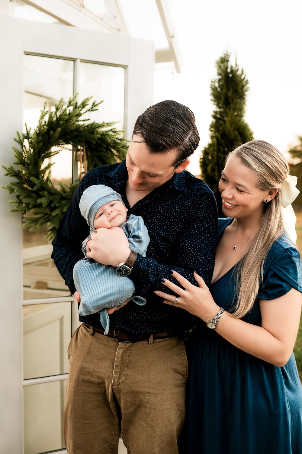 A family shares an intimate moment together by their front door decorated with holiday wreaths.