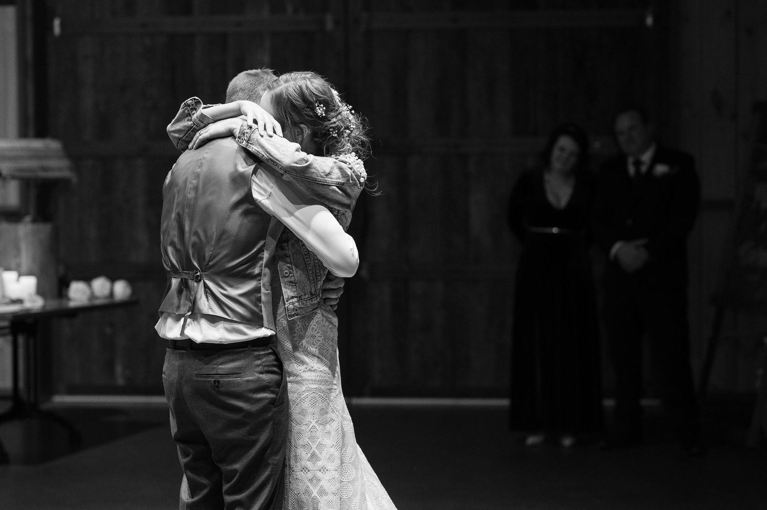 A couple dancing in a romantic embrace at a ballroom dance venue captured in black and white.