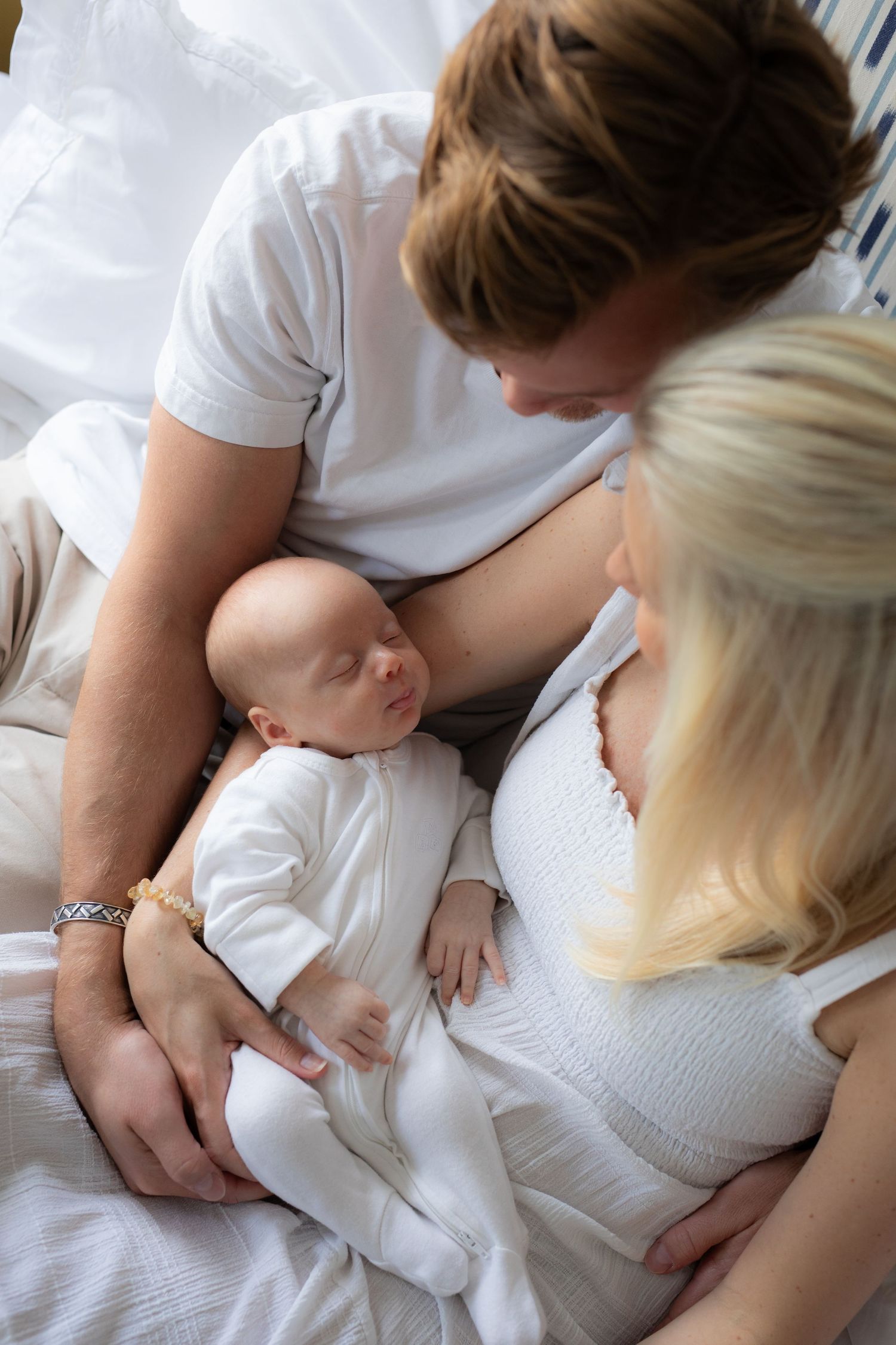 A series of intimate breastfeeding moments showing a mother nursing her baby while lying down on white bedding.