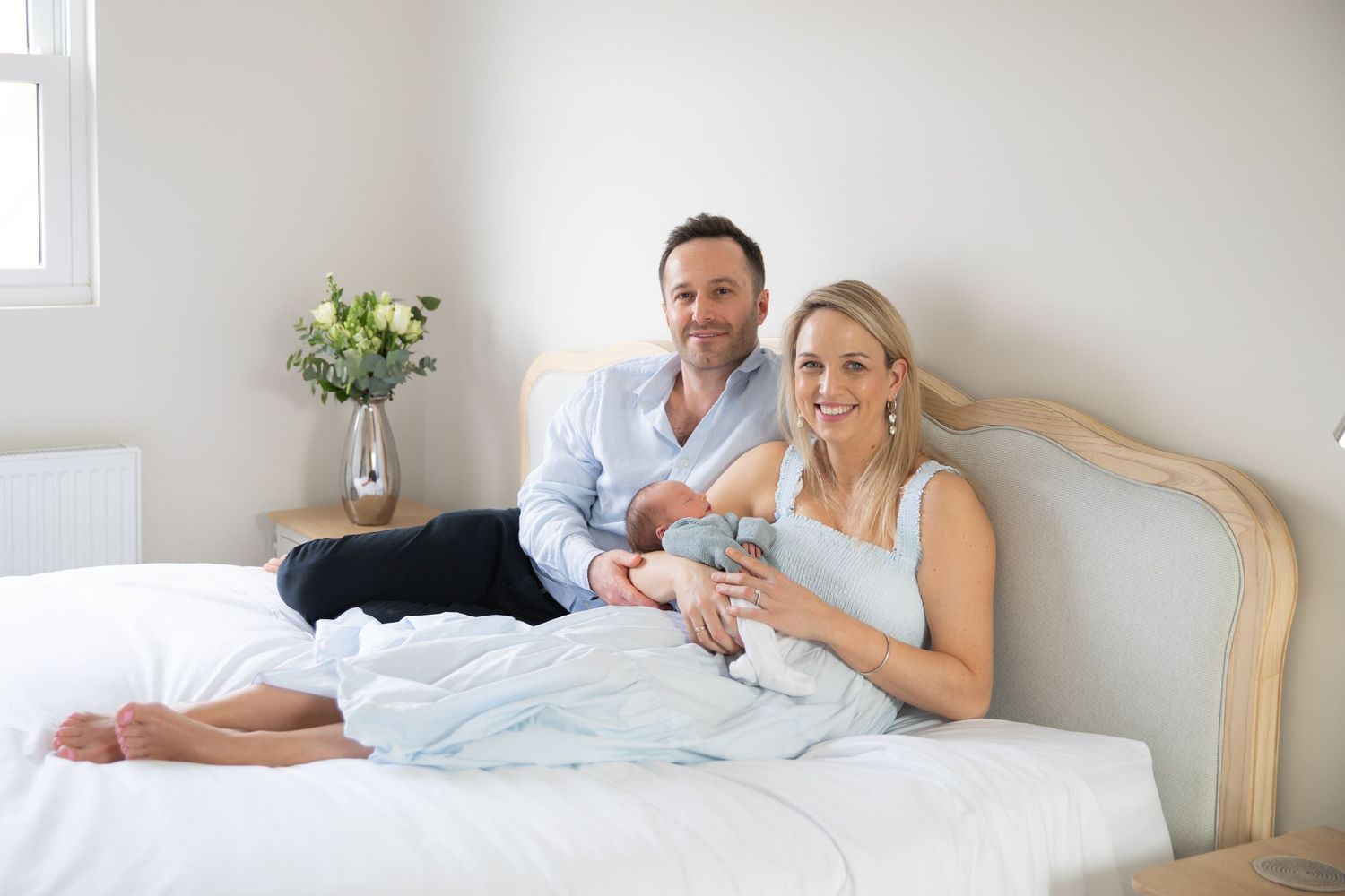 Two adults relaxing together in bed with tea while enjoying a casual morning at home.