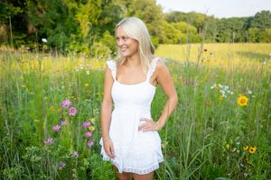 A woman in a white sundress stands in a vibrant wildflower meadow during golden hour.