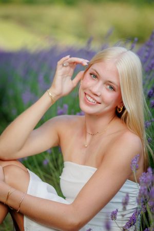 A white strapless dress contrasts beautifully against a blooming lavender field on a sunny summer day.