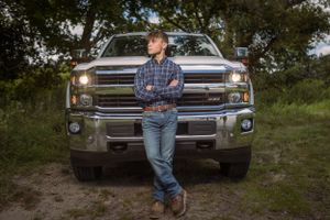 Pickup truck on dirt road with headlights on during sunset, styled country lifestyle portrait.