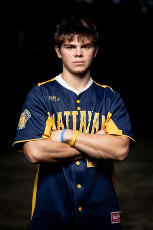 Athletic portrait of baseball player in navy and gold uniform with crossed arms.