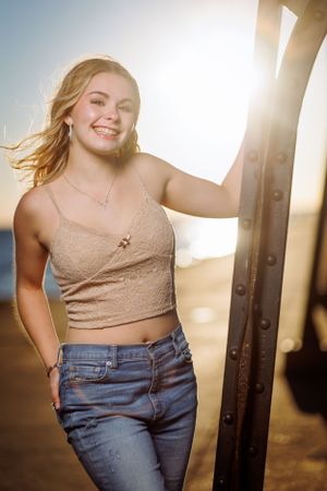 A person in a beige crop top and jeans poses outdoors during golden hour with sunlight creating a warm backlit glow.