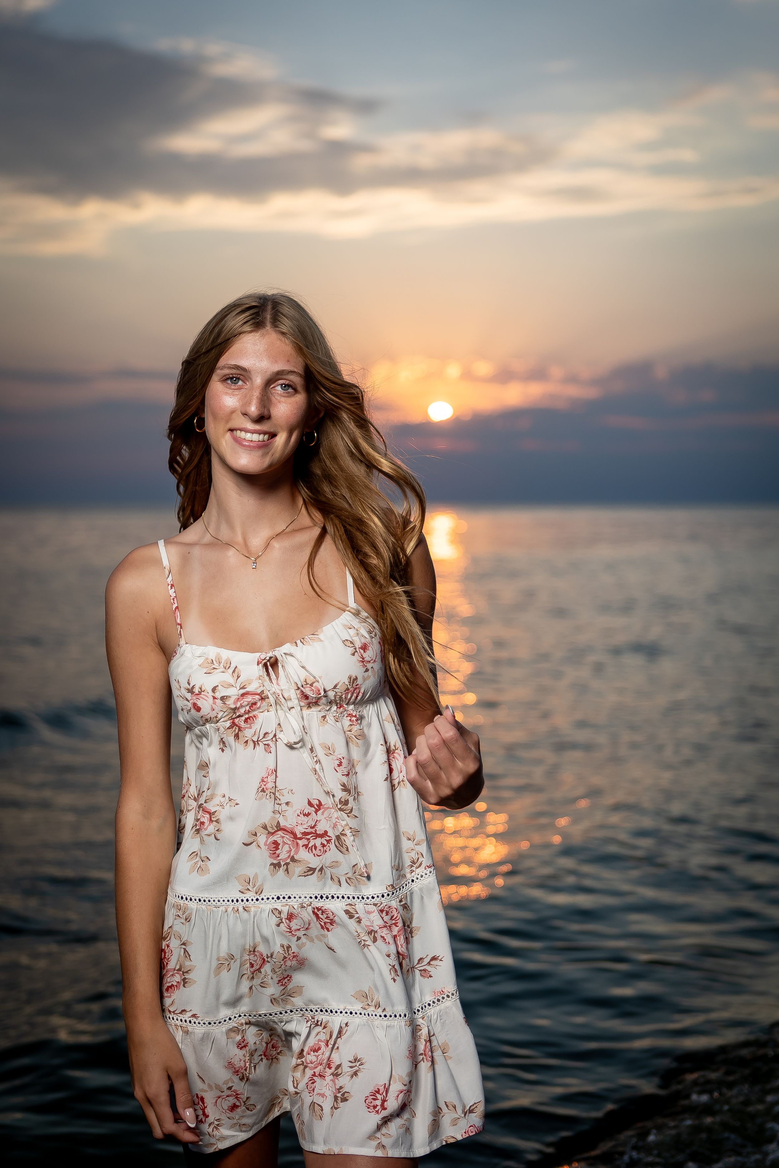 A series of sunset beach portraits showing someone in a floral white dress with flowing hair against the ocean backdrop.