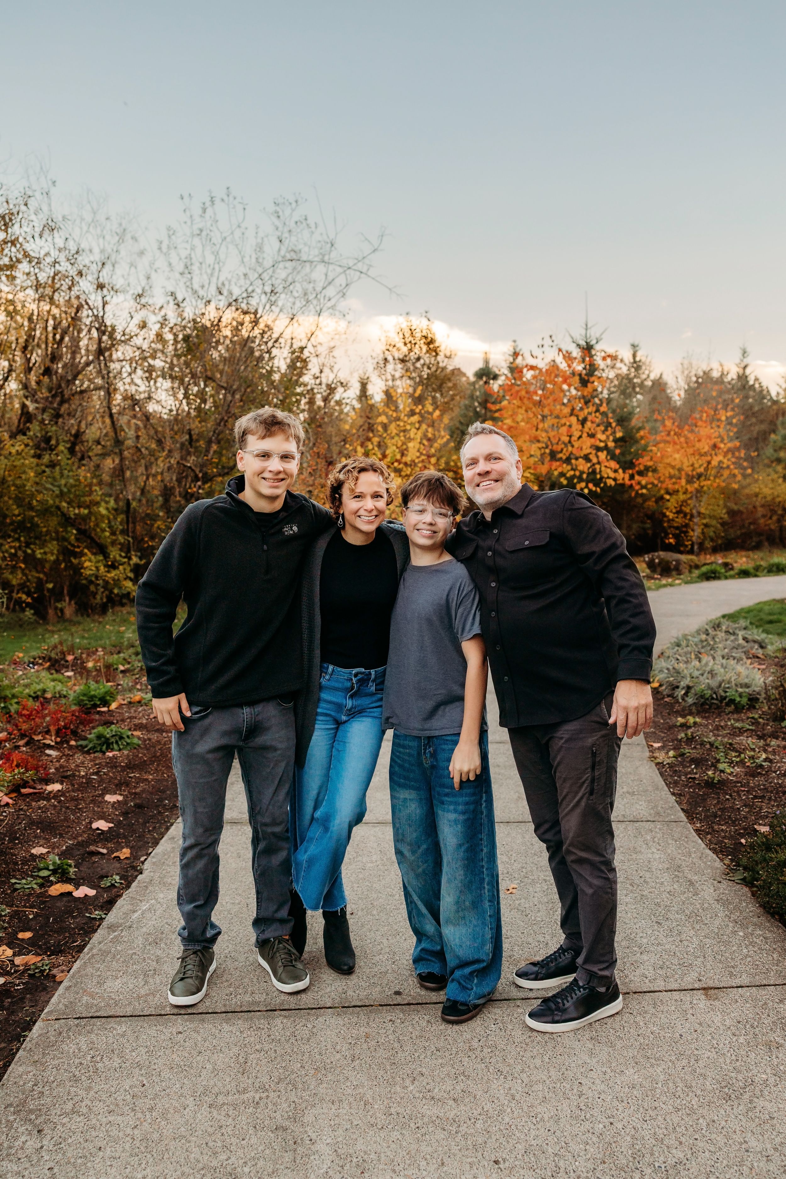 Family group poses together on garden path during autumn season.
