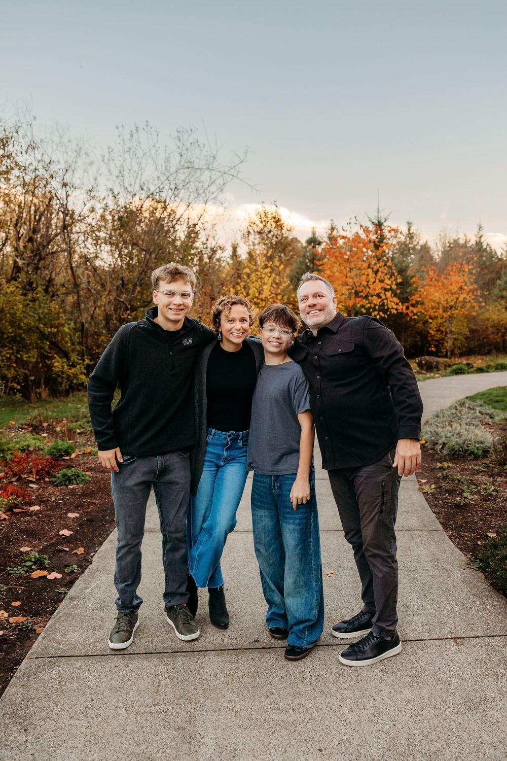 Family group poses together on garden path during autumn season.