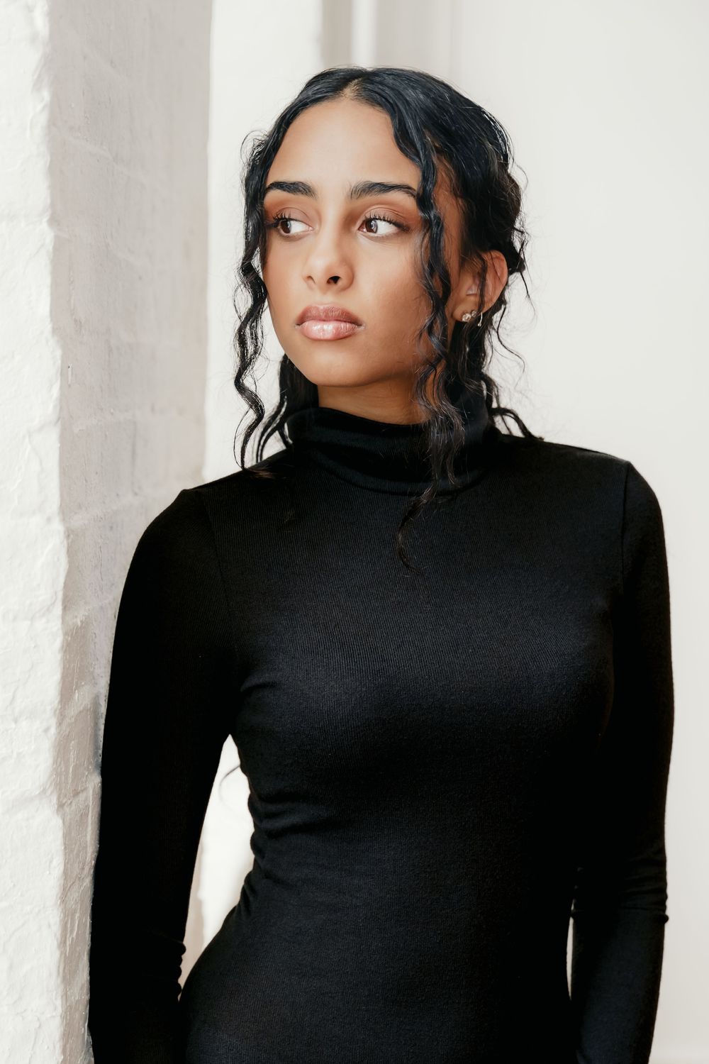 Portrait series of woman in black turtleneck against white background.