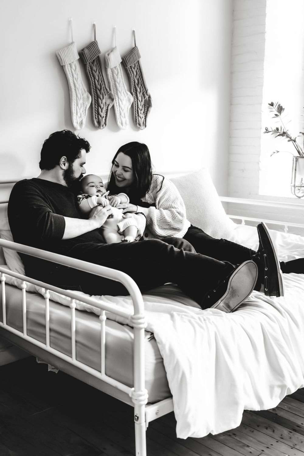 Black and white photo series of tender family moments on a white bed.