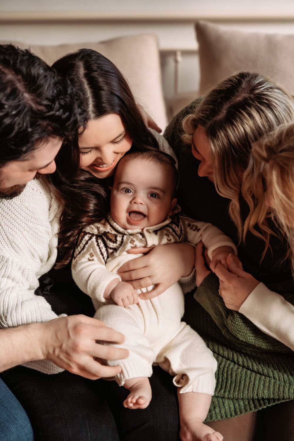Playful interaction between mother and baby on couch in cozy indoor setting.