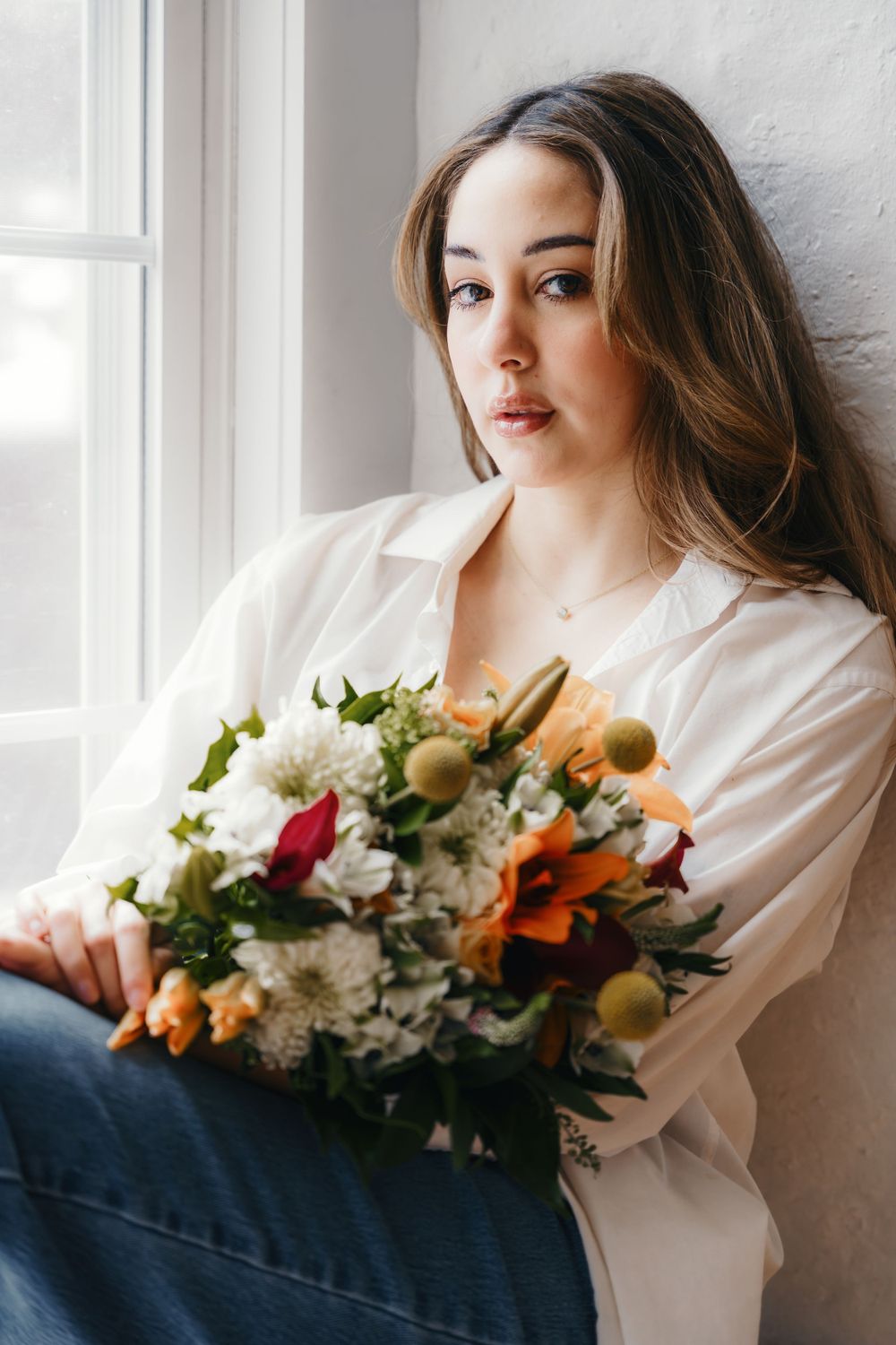 Artistic portrait series with mixed floral bouquet against white wall.