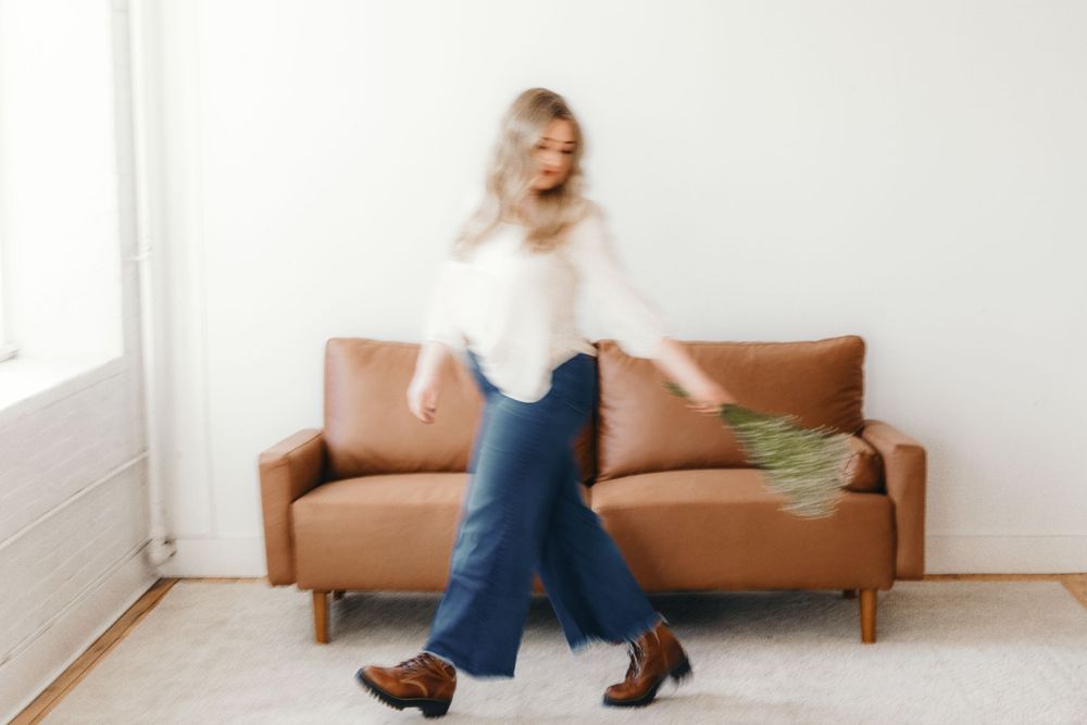 Minimalist portraits on brown leather couch in bright white room.