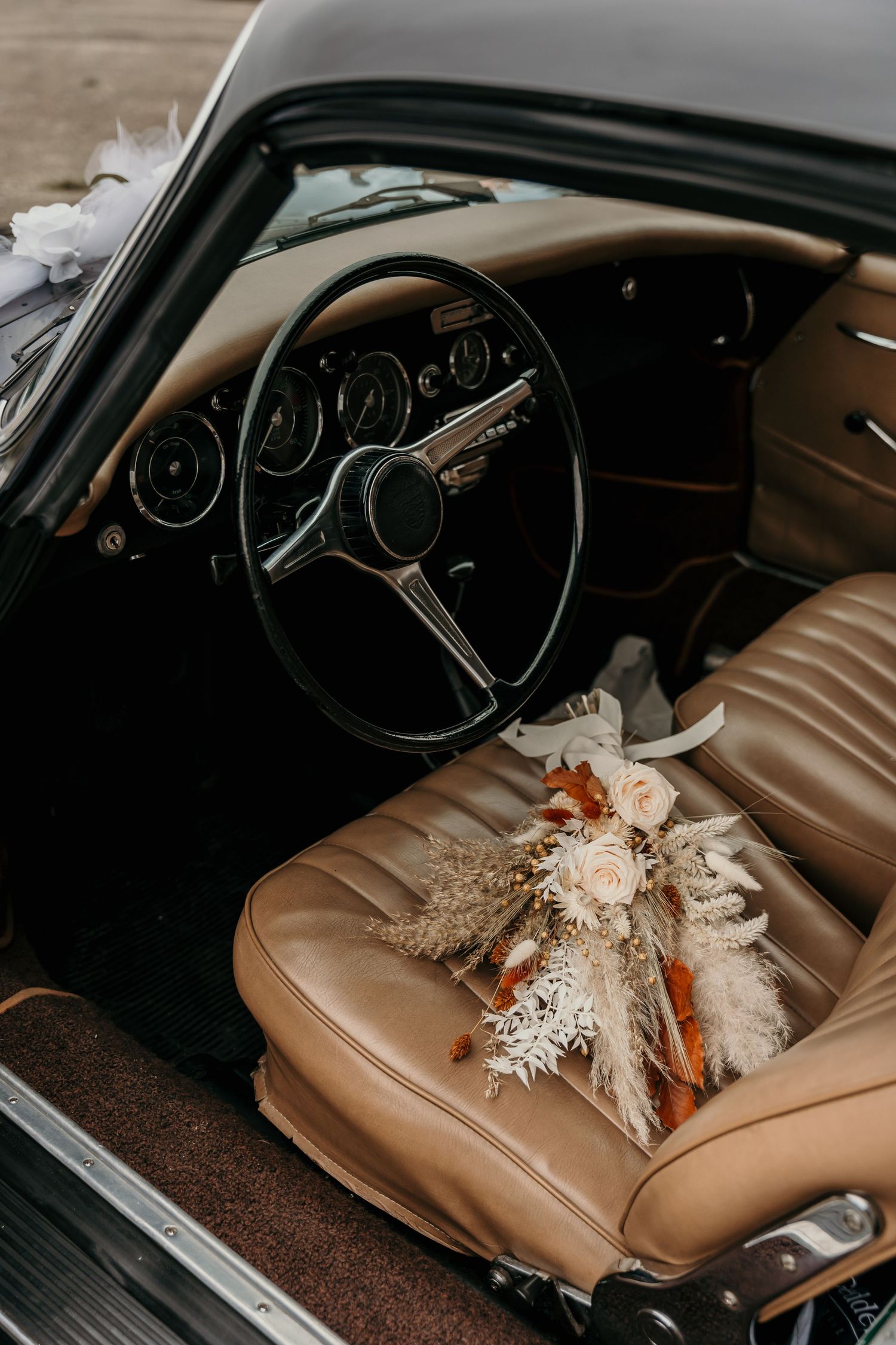 Een foto van een Porsche oldtimer met bruidsboeket.