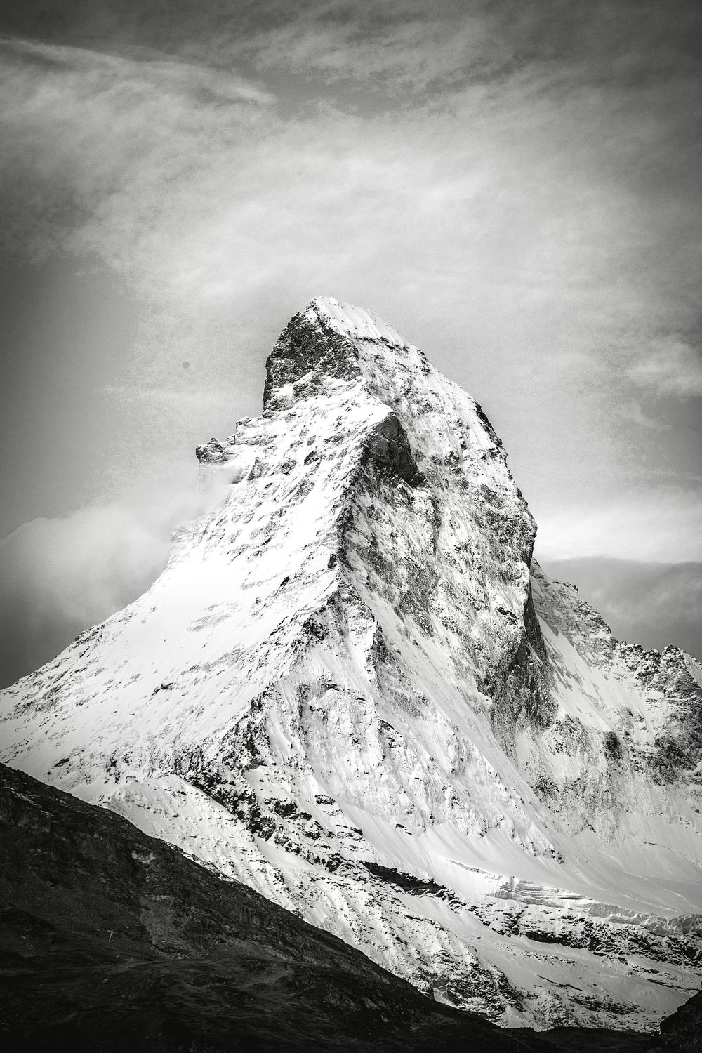 Dramatic black and white panoramic sequence showing a snow-covered mountain peak against a moody clouded sky.