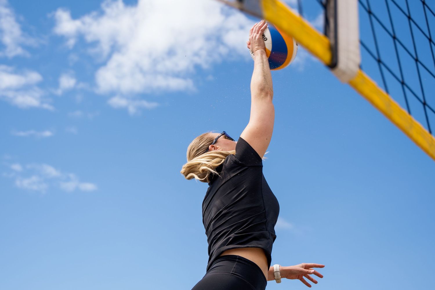 Beachvolleyballspiller som smasher ved nettet