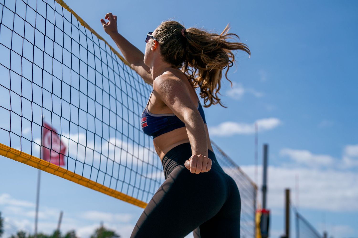 Beachvolleyballspiller som hopper opp på nett