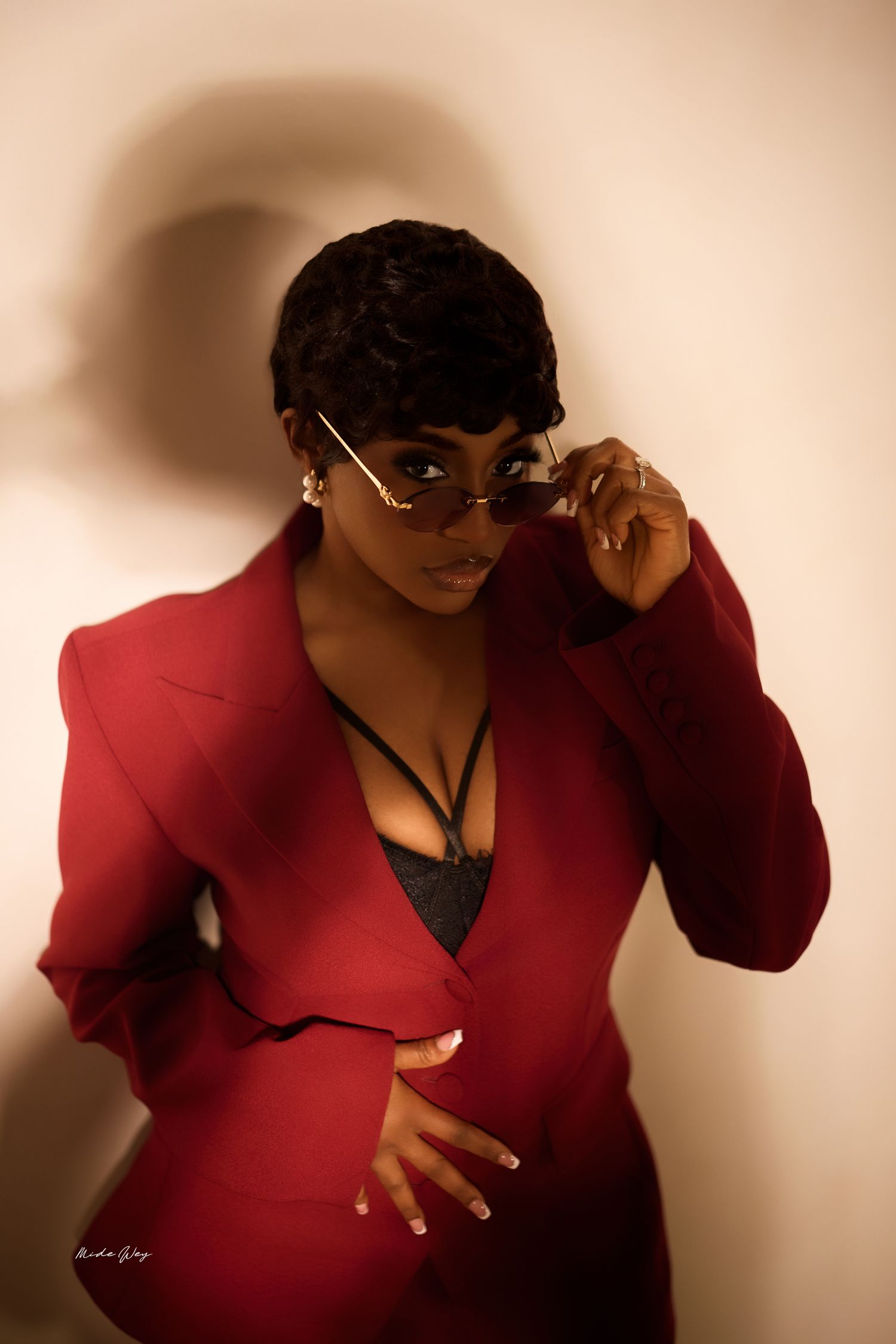 Person in a red blazer and sunglasses poses in a series of dramatic shots against a neutral background.